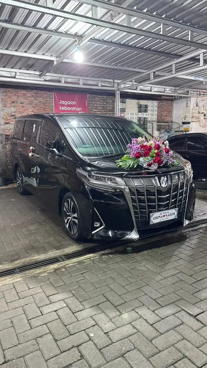 Mobil Alphard hitam dengan dekorasi bunga terparkir di garasi