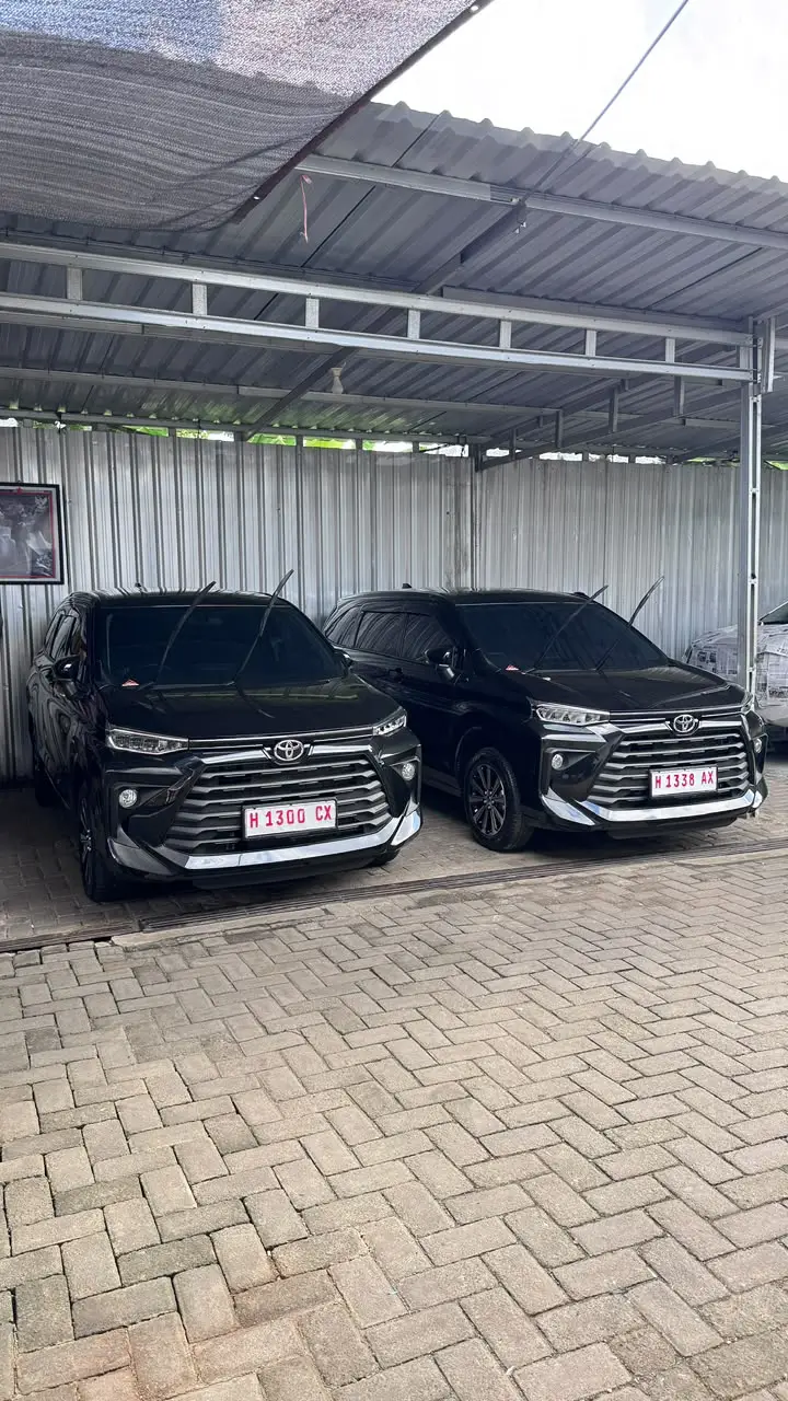 Dua mobil MPV hitam terparkir berdampingan di garasi